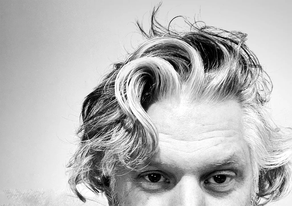Black and white close-up of Jeff from the eyes up, with long, unruly pandemic hair.