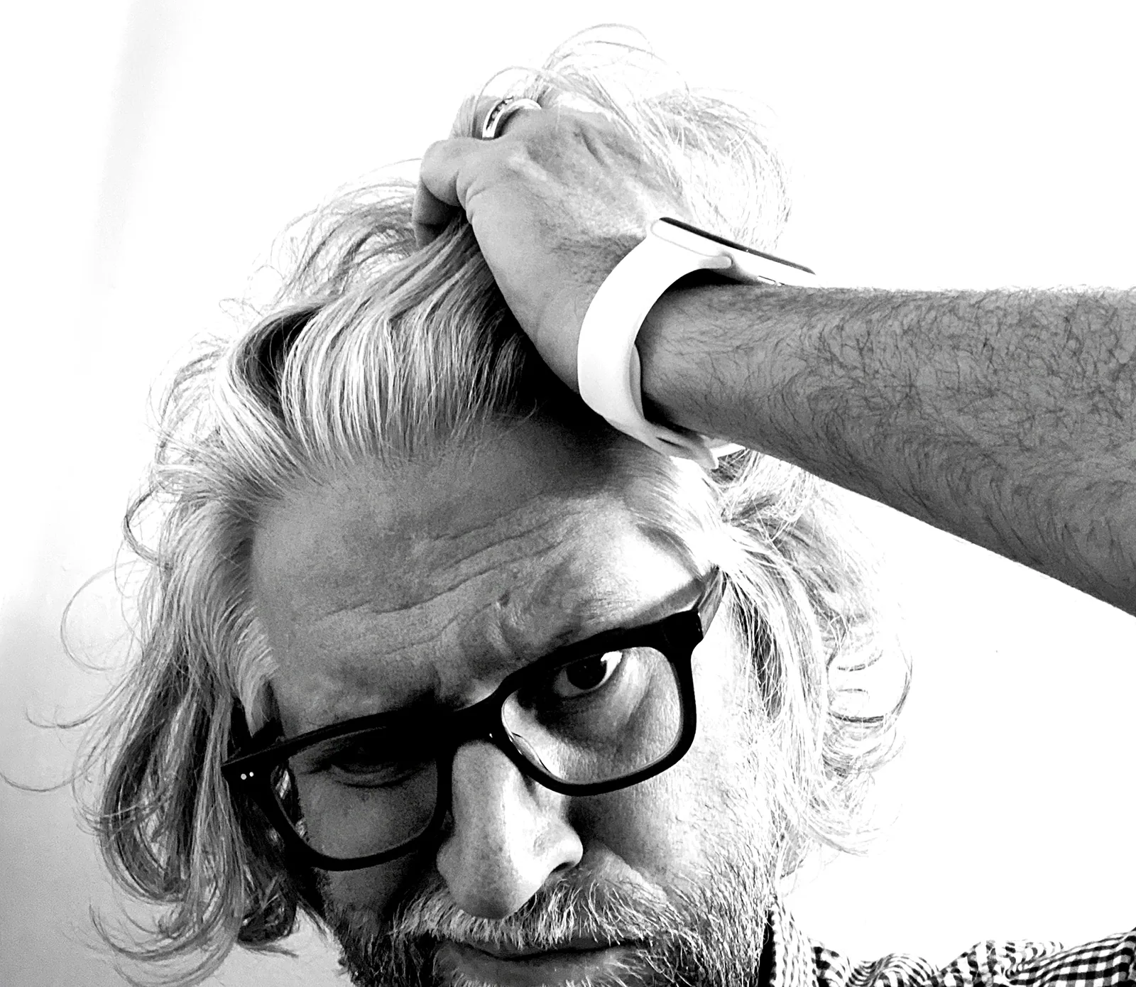 Black and white portrait of Jeff pushing his long hair back with one hand, wearing heavy dark-framed glasses.