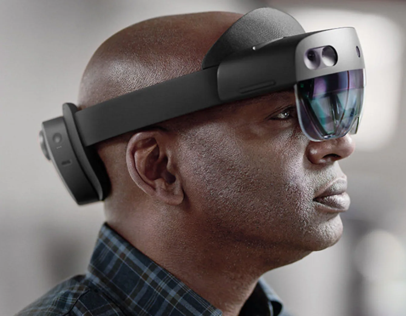 A man wearing an augmented reality headset, a padded band circling his head with a transparent visor over his eyes.